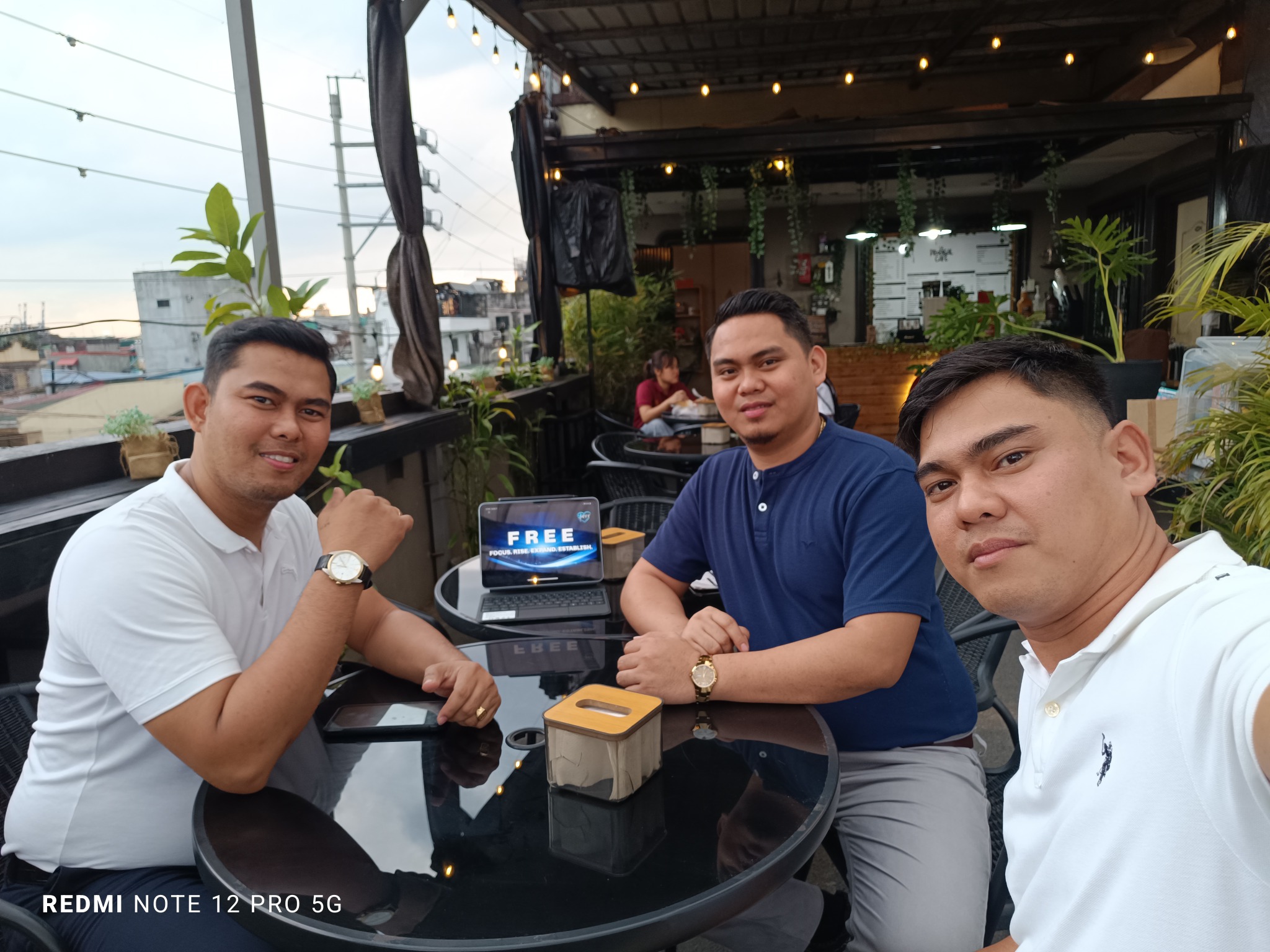Three F.R.E.E. Framework members meet around a table outdoors